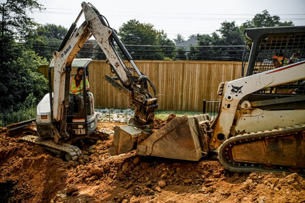 Two operators using machinery to move dirt materials on a jobsite.