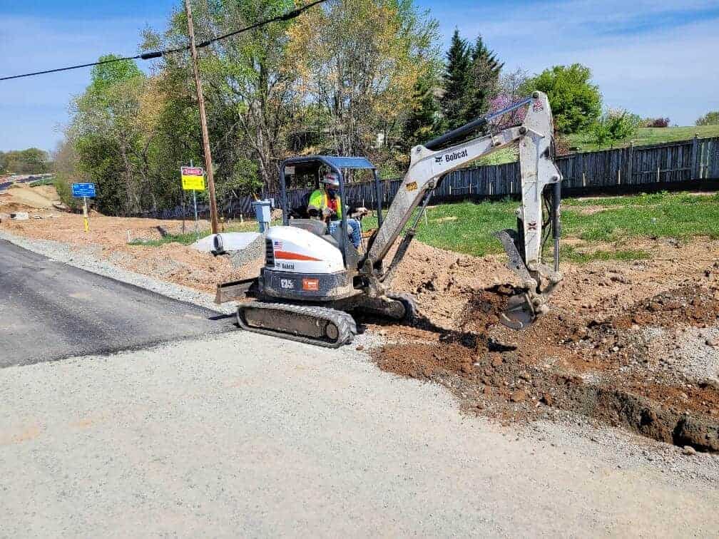 Muller operator working on the side of a road digging to install an example of dry utilities