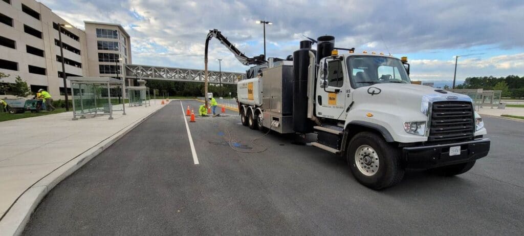 Men working with a white Muller Inc. truck in the road for hydro excavation services