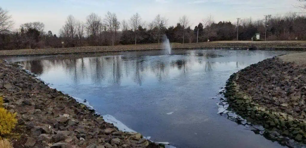 Large pond with a fountain in the middle and rocks around it as an important storm drain measure