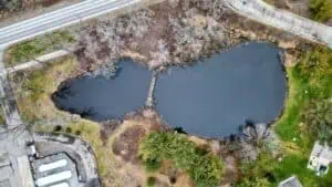 Aerial view of a stormwater pond surrounded by roads, trees, and developed land.